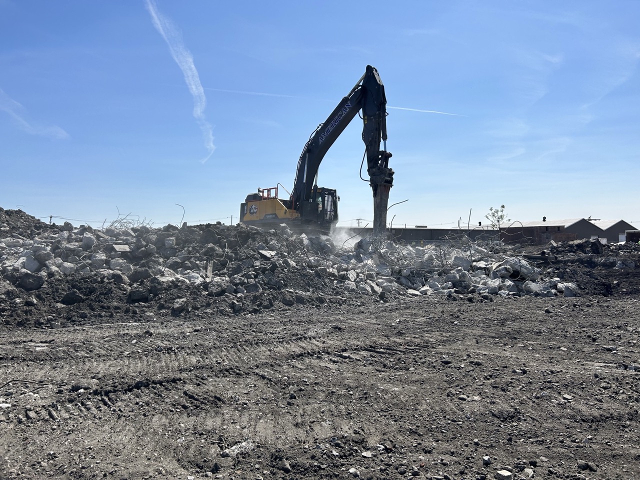 Excavator breaking up concrete and construction debris during Chelsea Point site demolition in Franklin, MA