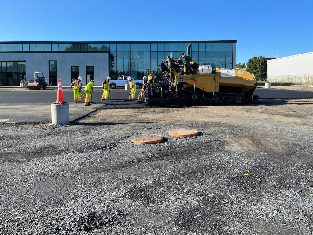 Construction crew performing asphalt paving work in parking lot at 24M Westwood development