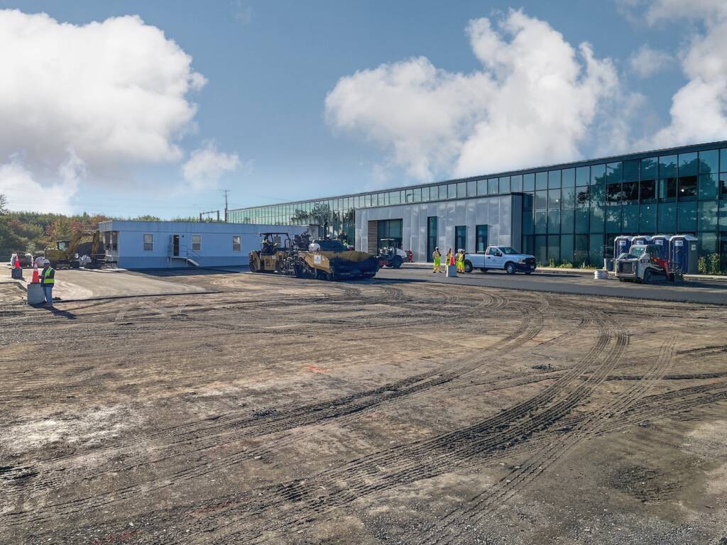 Wide view of paving operations and site work at 24M Westwood including heavy equipment and newly graded surface