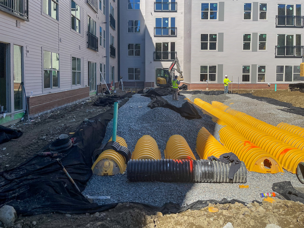 Stormwater infiltration system with subsurface chambers installed beneath courtyard at apartment community in Stoneham, Massachusetts