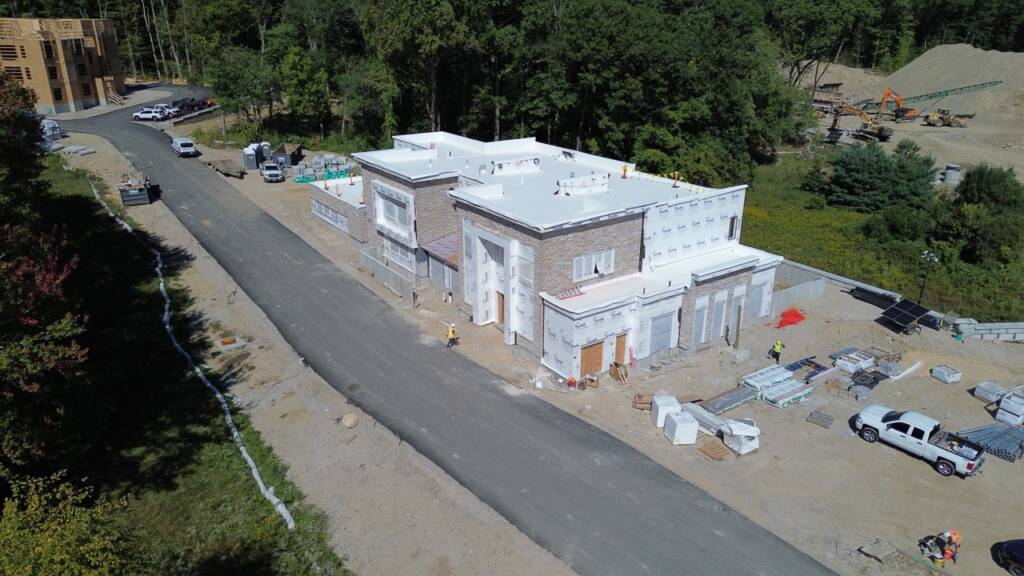 Aerial construction photo showing paved site roadway and clubhouse building at Franklin Grove Apartments in Franklin, MA.